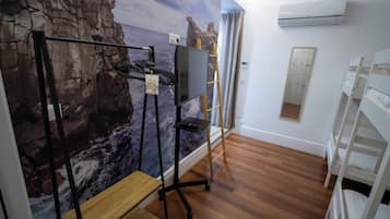 Ein Zimmer mit Holzboden, Schreibtisch mit Stuhl, Wandfernseher und einer Wandmalerei mit Felswand.