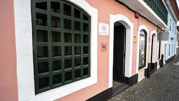 Un edificio con un gran ventanal arqueado, un cartel que dice 'Aurora Hostel' y una vista de la calle con pavimento de adoquines.