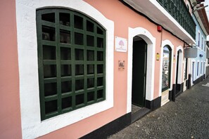 Un edificio con un gran ventanal arqueado, un cartel que dice 'Aurora Hostel' y una vista de la calle con pavimento de adoquines.