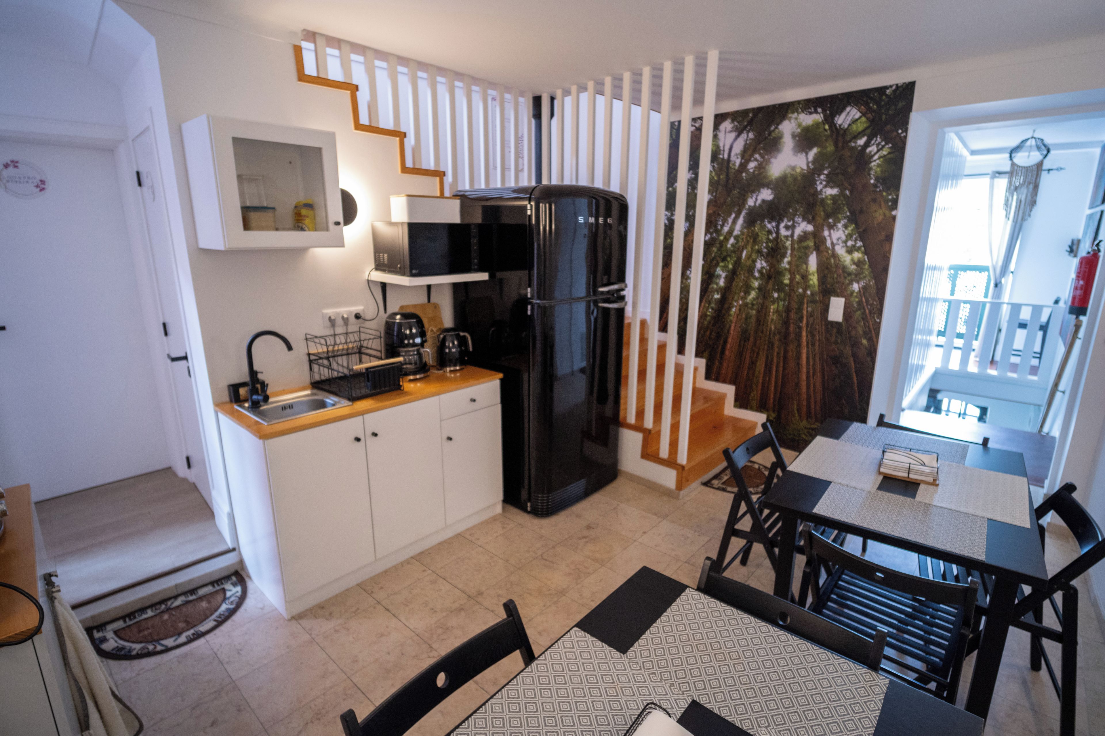 Una cocina compacta con refrigerador, microondas y cafetera.