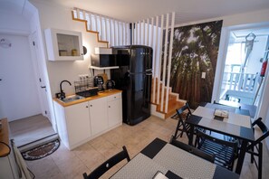 Una cocina compacta con refrigerador, microondas y cafetera.