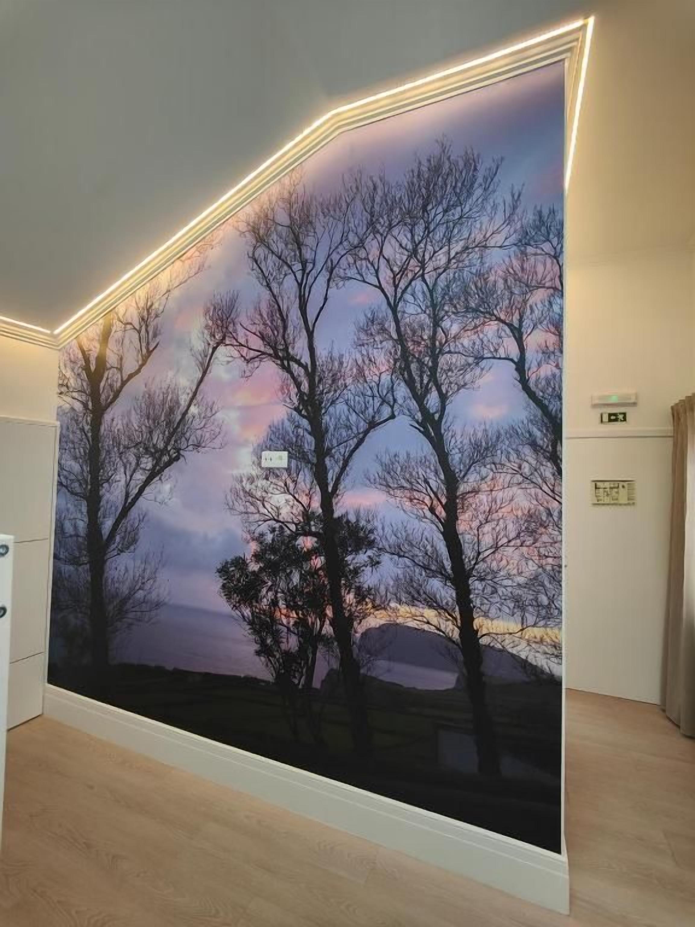 A room with a large wall mural depicting trees and a sunset.