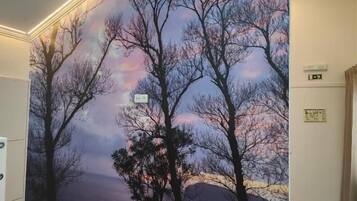 A room with a large wall mural depicting trees and a sunset.