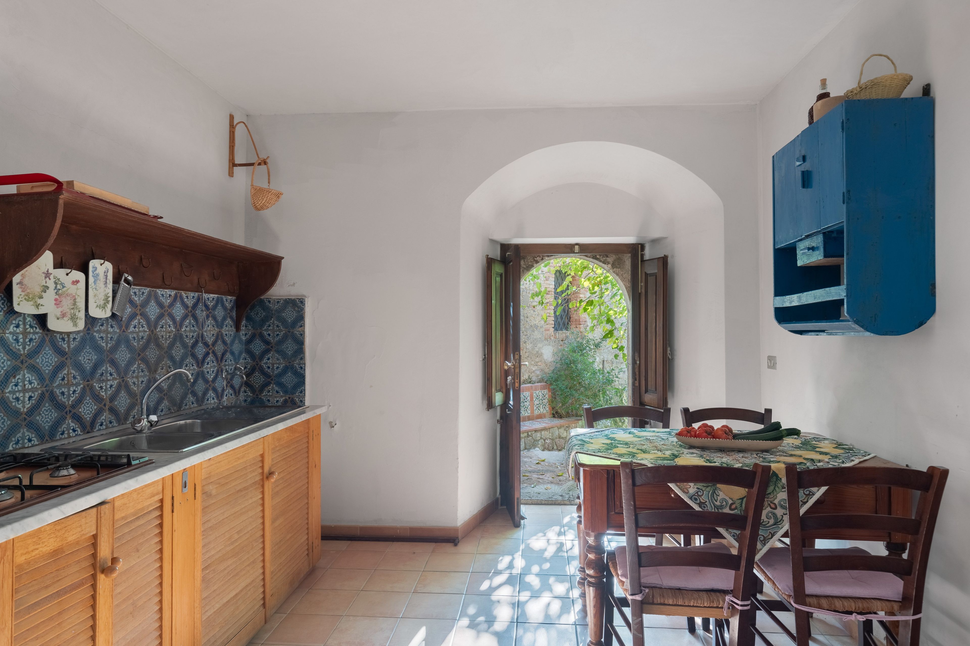 A kitchen with a tiled backsplash, wooden cabinets, a sink, and a dining area with a table and chairs.