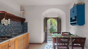 A kitchen with a tiled backsplash, wooden cabinets, a sink, and a dining area with a table and chairs.