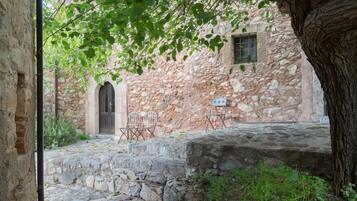 An outdoor courtyard with stone walls, a wooden door, and two metal chairs.