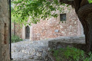 An outdoor courtyard with stone walls, a wooden door, and two metal chairs.