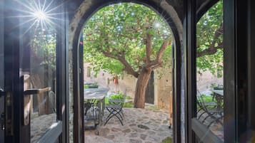 An outdoor patio area with stone flooring, a table, chairs, and a tree.