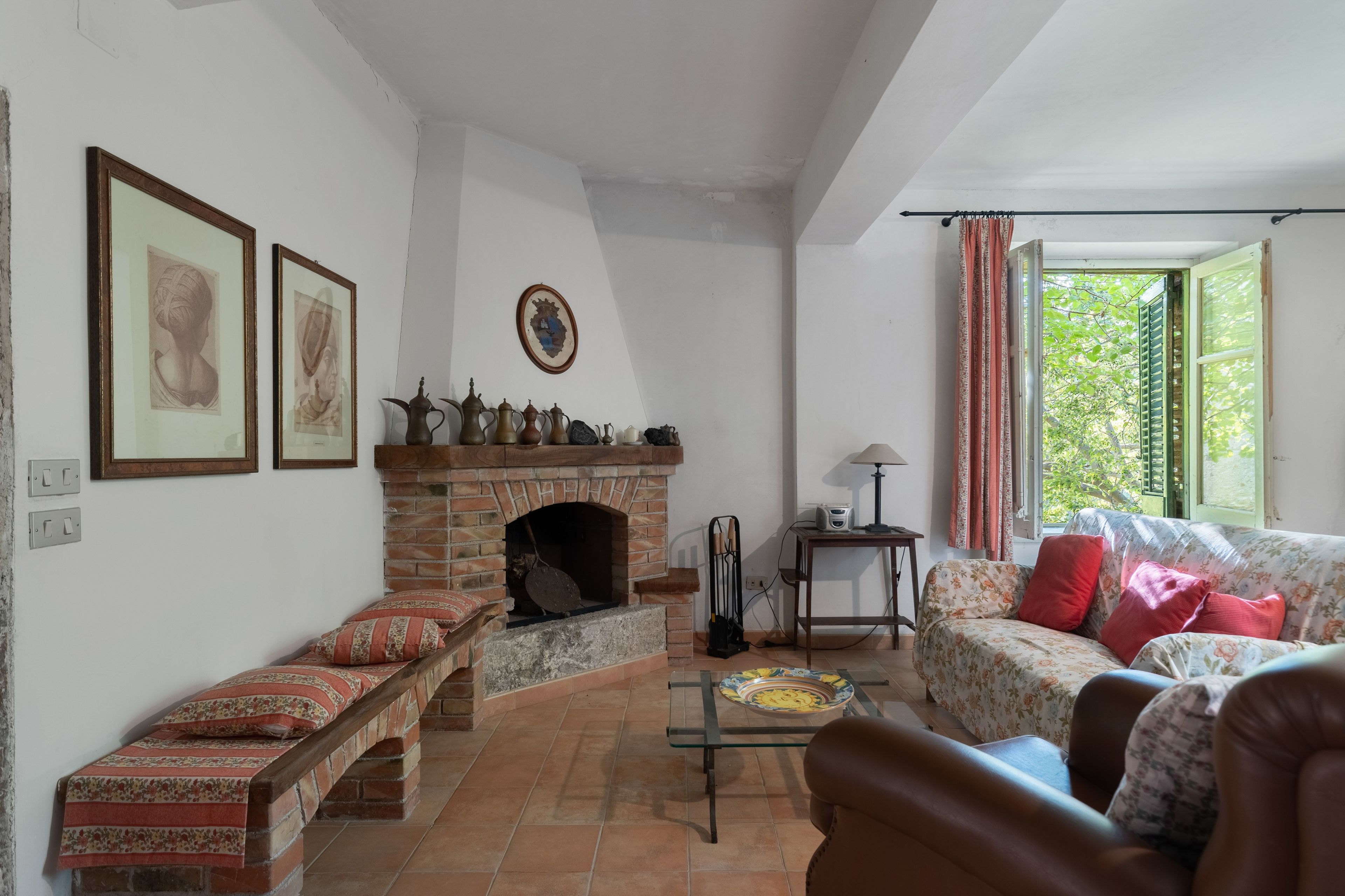 Una sala de estar con chimenea, un sofá, una mesa de centro y un ventanal con cortinas.