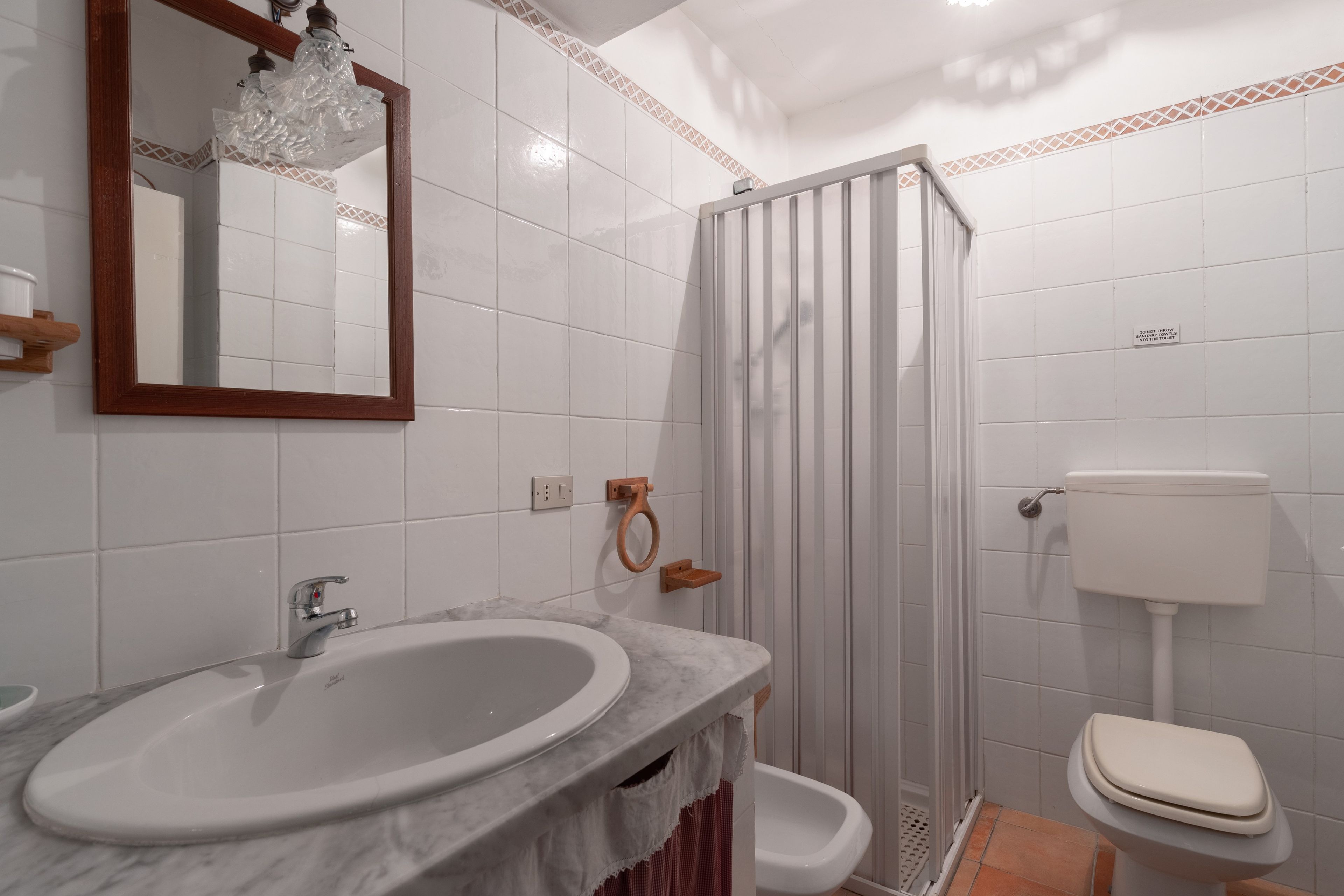 Un bagno con lavabo in marmo, un water e cabina doccia.