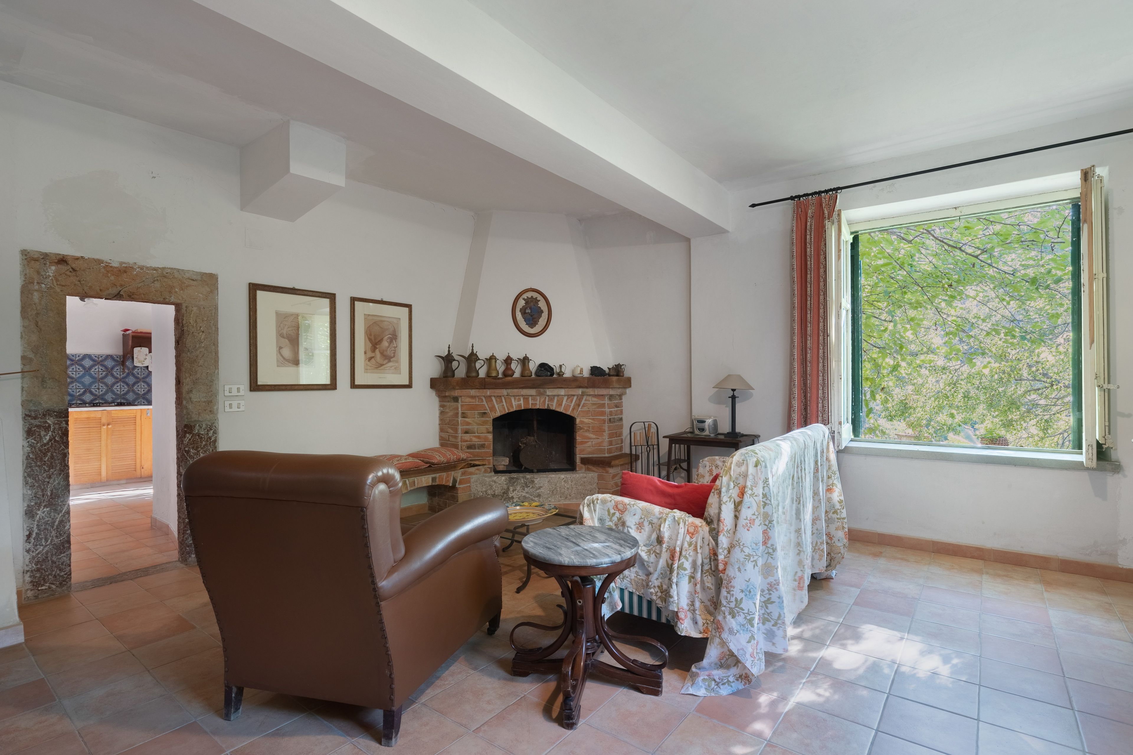 Un salon avec une cheminée, un canapé, une table et une fenêtre avec des rideaux.
