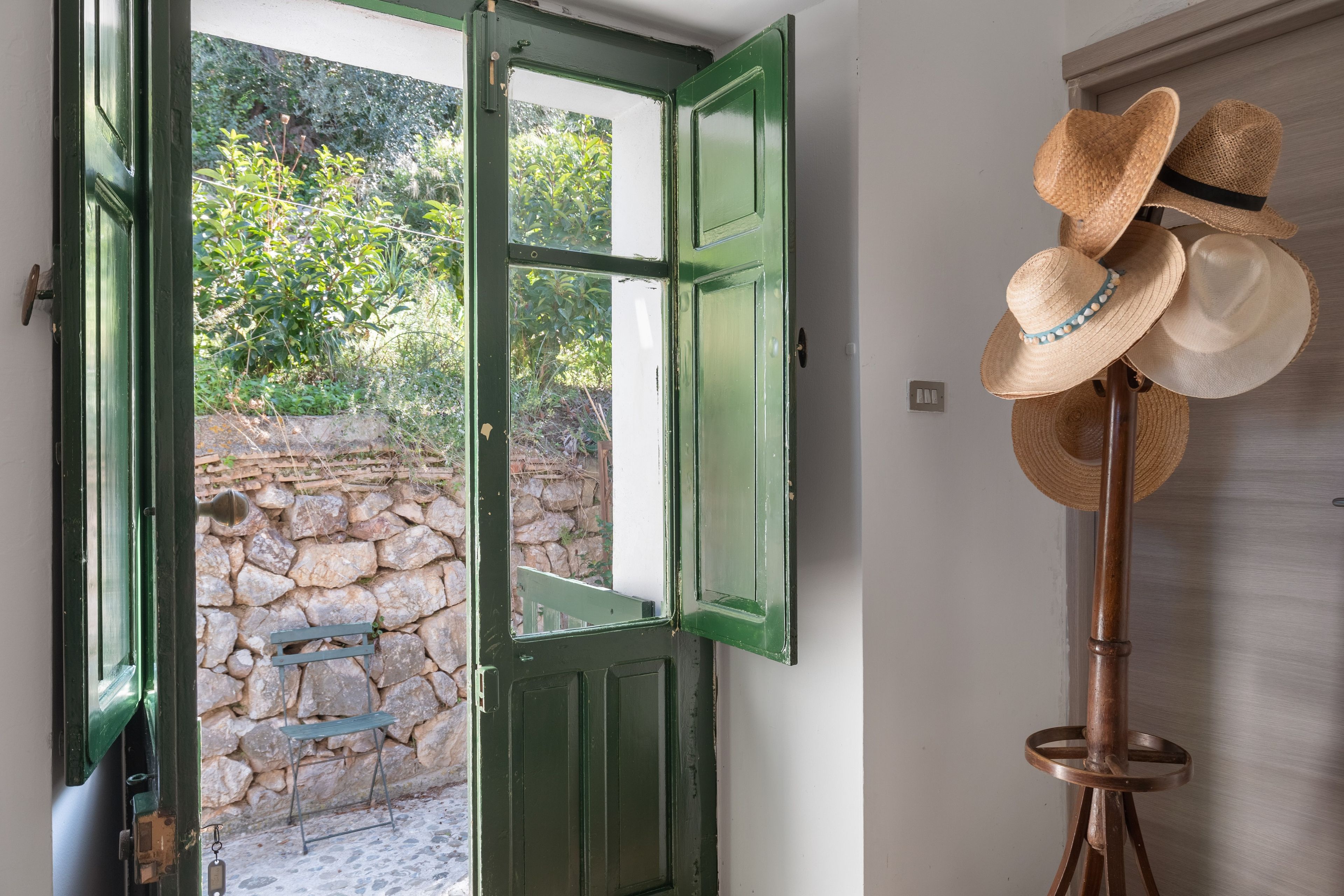 A room with a green door leading to a stone wall and a small bench.