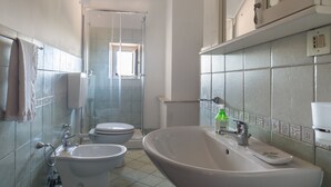 A bathroom with two toilets, a sink, and a shower area. - Apartment on the oil mill (Torrenova)