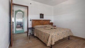 A bedroom with a wooden bed, a small bedside table, a nightstand, a wall-mounted picture, and a door leading to another room. - Apartment on the oil mill (Torrenova)