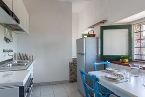 A kitchen with a refrigerator, sink, and a window with a view of the outside.