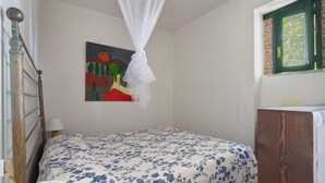 A bedroom with a bed, a painting, a window, and a bedside table. - Azienda Agricola Santo Pietro - Il Frantoio (Torrenova)