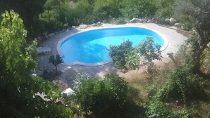 A swimming pool surrounded by greenery, with a bench and a covered area nearby. - Azienda Agricola Santo Pietro - Il Frantoio (Torrenova)