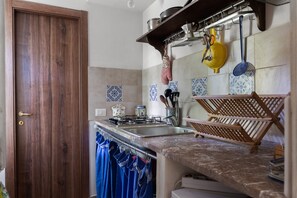Cuina amb porta de fusta, respatller de rajoles i prestatge per penjar cassoles.