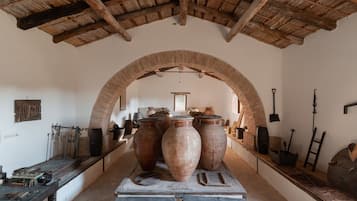 An interior with a vaulted ceiling, large pottery, and traditional tools.