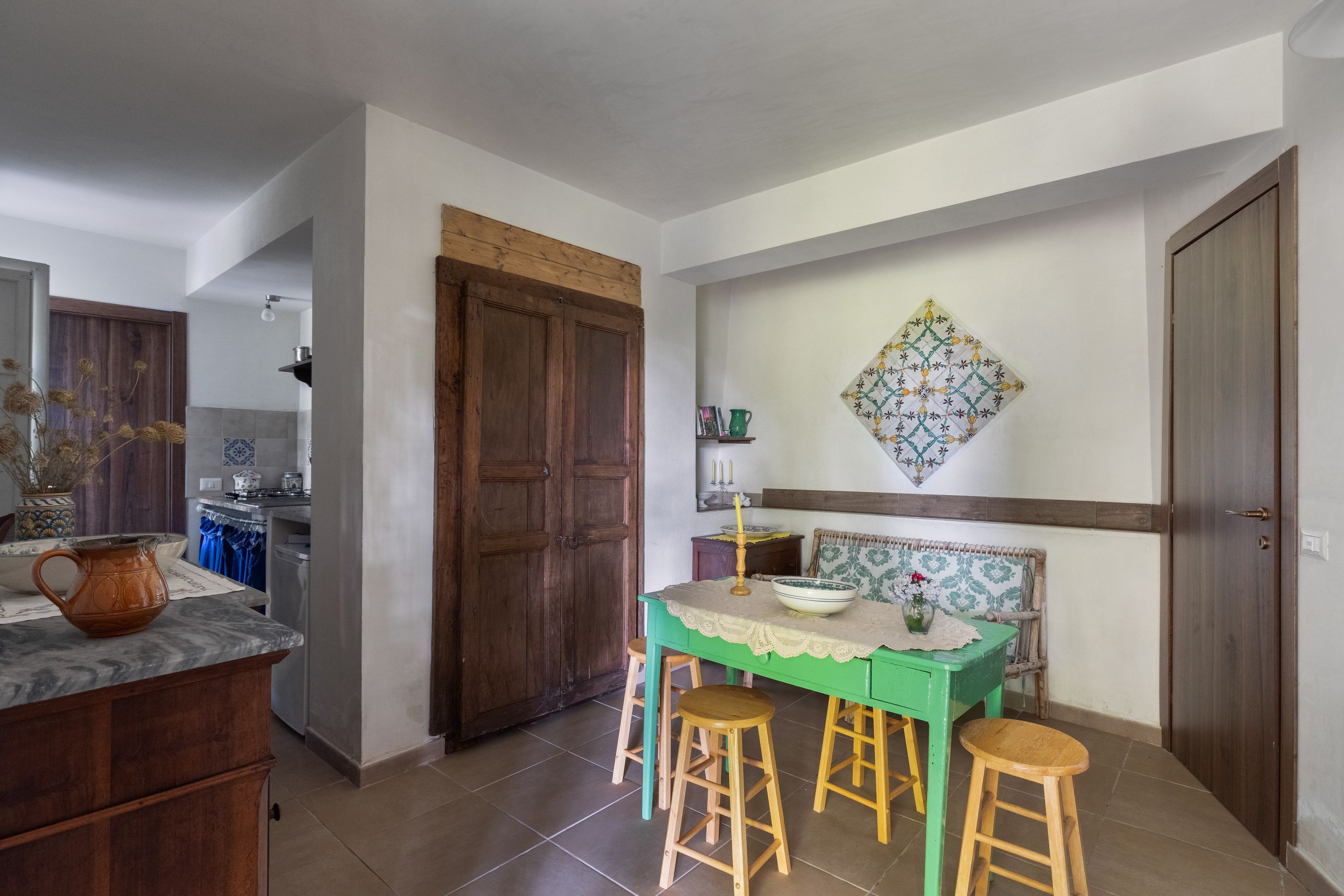 Un comedor con una mesa, taburetes, un adorno en la pared y una puerta de madera.