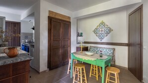 A dining area with a table, stools, a decorative wall piece, and a wooden door. - Azienda Agricola Santo Pietro - Il Frantoio (Torrenova)