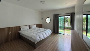 Un dormitorio moderno con una cama grande, un espejo redondo y una puerta corredera de vidrio que da a un balcón.