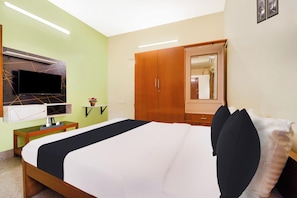 Quarto de hotel com cama, televisão na parede, guarda-roupa e espelho.