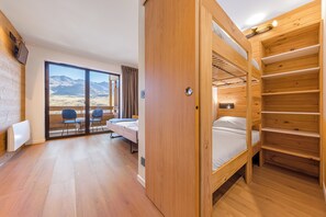 A room with a bunk bed, a desk, and a chair, with a large window offering a mountain view. - “V21” by Versant Collection (Val Thorens)