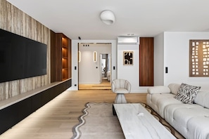 Ein modernes Wohnzimmer mit Flachbildfernseher, einer Couch, einem gemusterten Teppich und einem minimalistischen Design.