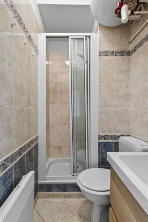 A bathroom with a shower enclosure, toilet, and a bathtub. - Flexible Lease – Modern – 1 Bedroom – Parisian Charm (Levallois-Perret)