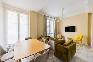 A modern living room with a dining table, sofas, and a TV mounted on the wall. - Rome - Premium - Parc Monceau - Villiers - 5-Bedroom - Haussmann Style (Paris)