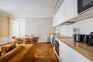 A modern kitchen with a dining area, wooden flooring, and a built-in oven. - Rome - Premium - Parc Monceau - Villiers - 5-Bedroom - Haussmann Style (Paris)