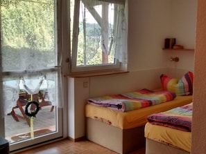 Un dormitorio con ventana, cama y una pequeña estantería.