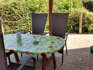 Un patio al aire libre con mesa y sillas, rodeado de vegetación.
