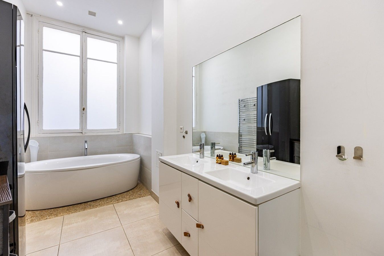 A modern bathroom with a bathtub, a large mirror, and a vanity with a sink.