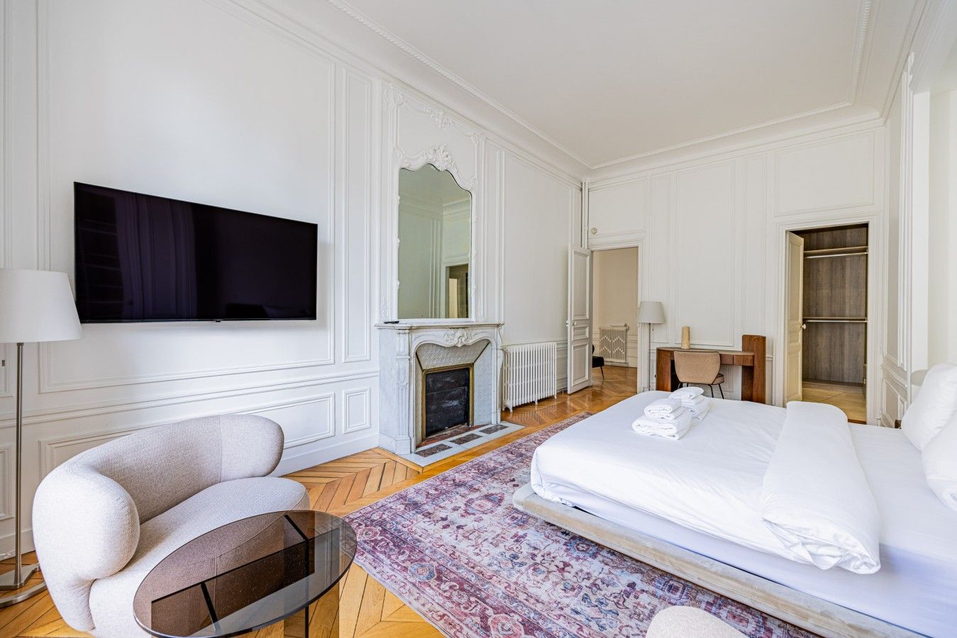 A hotel room with a bed, a television, a fireplace, a desk, and a chair.