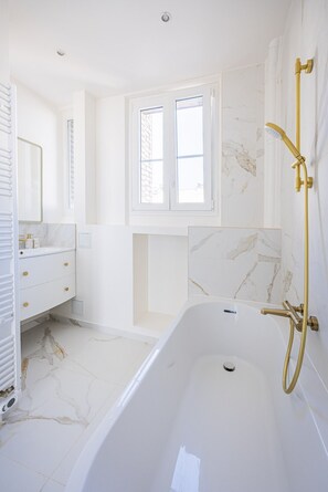 Een moderne badkamer met een bad, een wastafel met spiegel en een raam.