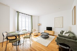 Een moderne woonkamer met een eethoek, een flatscreen televisie en een bank.