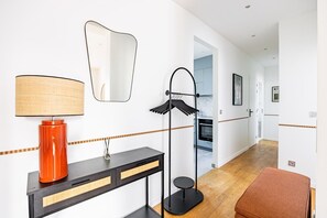 Ein modernes Interieur mit einem Konsolentisch, einer Lampe, einem Spiegel und einer Stehlampe.