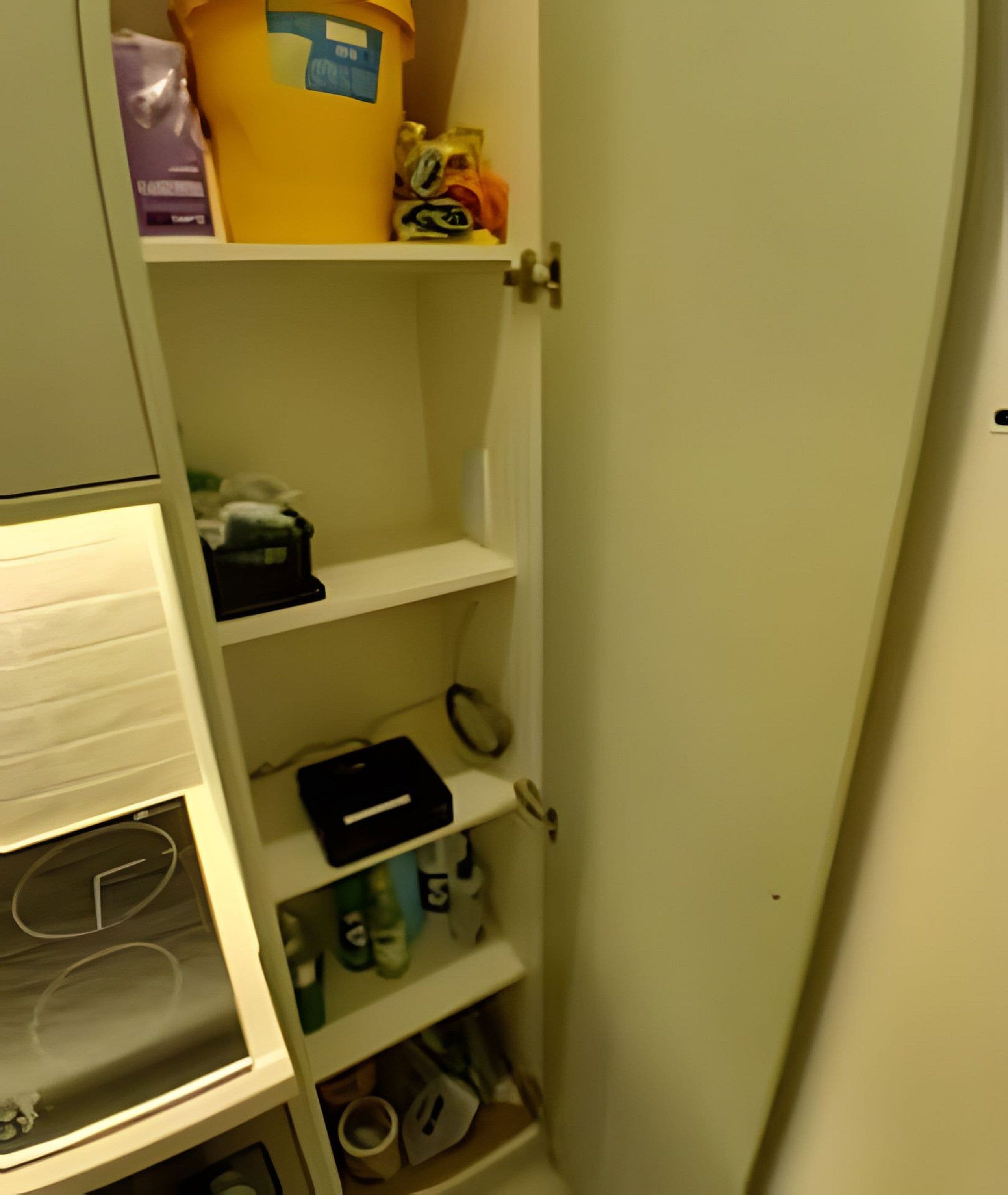 A storage area with shelves containing various items including a yellow container, a black box, and some folded clothes.