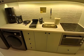 A compact kitchenette with a coffee maker, scale, kettle, and microwave.
