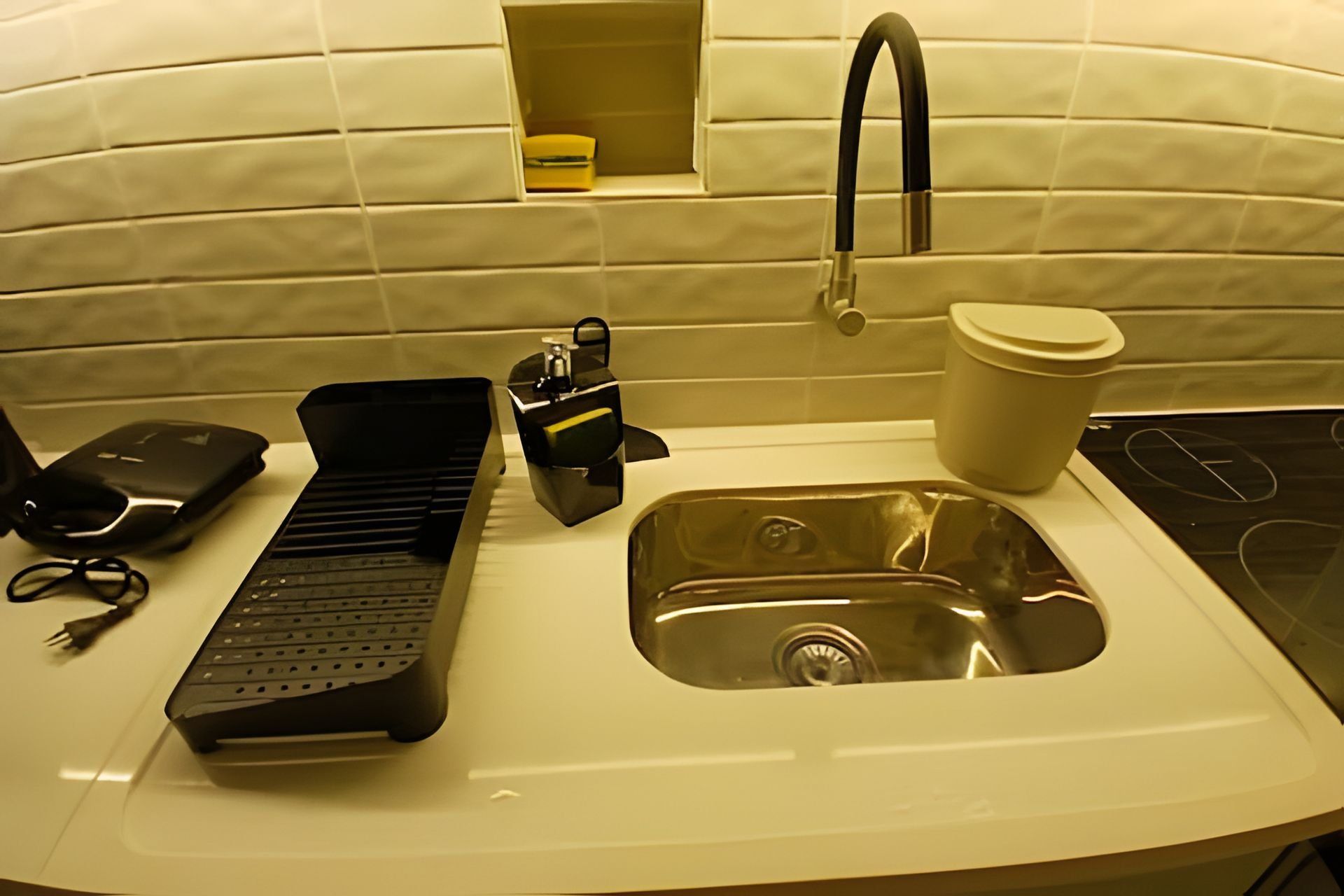 A kitchen with a sink, a kettle, a coffee cup, and a keyboard.