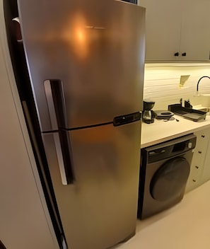 A stainless steel refrigerator with a black handle, a built-in coffee maker, and a dishwasher.