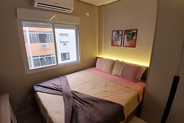 A bedroom with a bed, a window, and two wall-mounted artworks.
