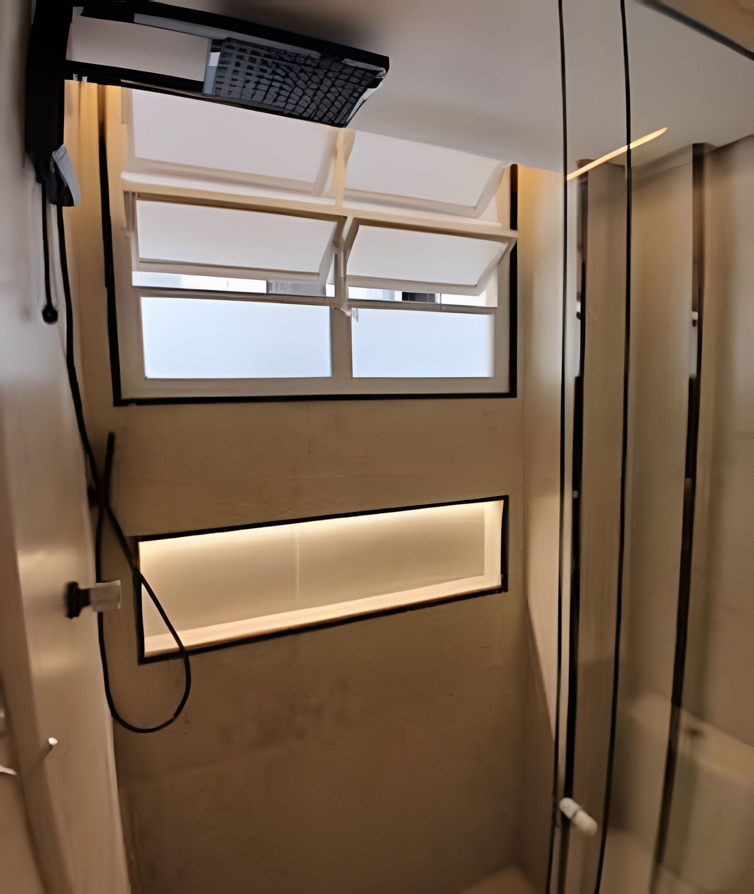 Un baño con ducha, ventana y luminaria.