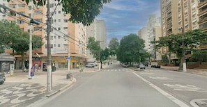 A street view with multi-story residential buildings, a visible storefront, and a bicycle parked on the sidewalk.