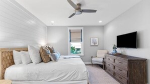 A bedroom with a bed, a dresser, a chair, a television, and a ceiling fan. - Seagrove Groove D102-Beach Access-Sleeps 8 (Seagrove Beach)