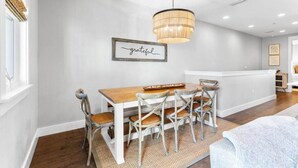 A dining area with a wooden table and chairs, a hanging light fixture, and a framed sign on the wall. - Seagrove Groove D102-Beach Access-Sleeps 8 (Seagrove Beach)