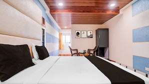 A hotel room with a large bed, a wooden ceiling, and a small seating area with a table and chairs. - Hotel O Palava Dombivali (Mumbai)