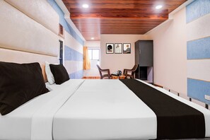 Habitació d'hotel amb un llit gran, un sostre de fusta i una petita zona de seients amb taula i cadires.
